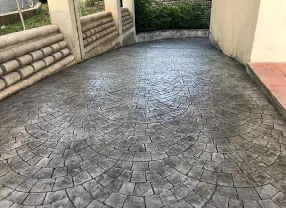 Entrada curva de hormigón impreso con molde de adoquín redondo gris en abanico