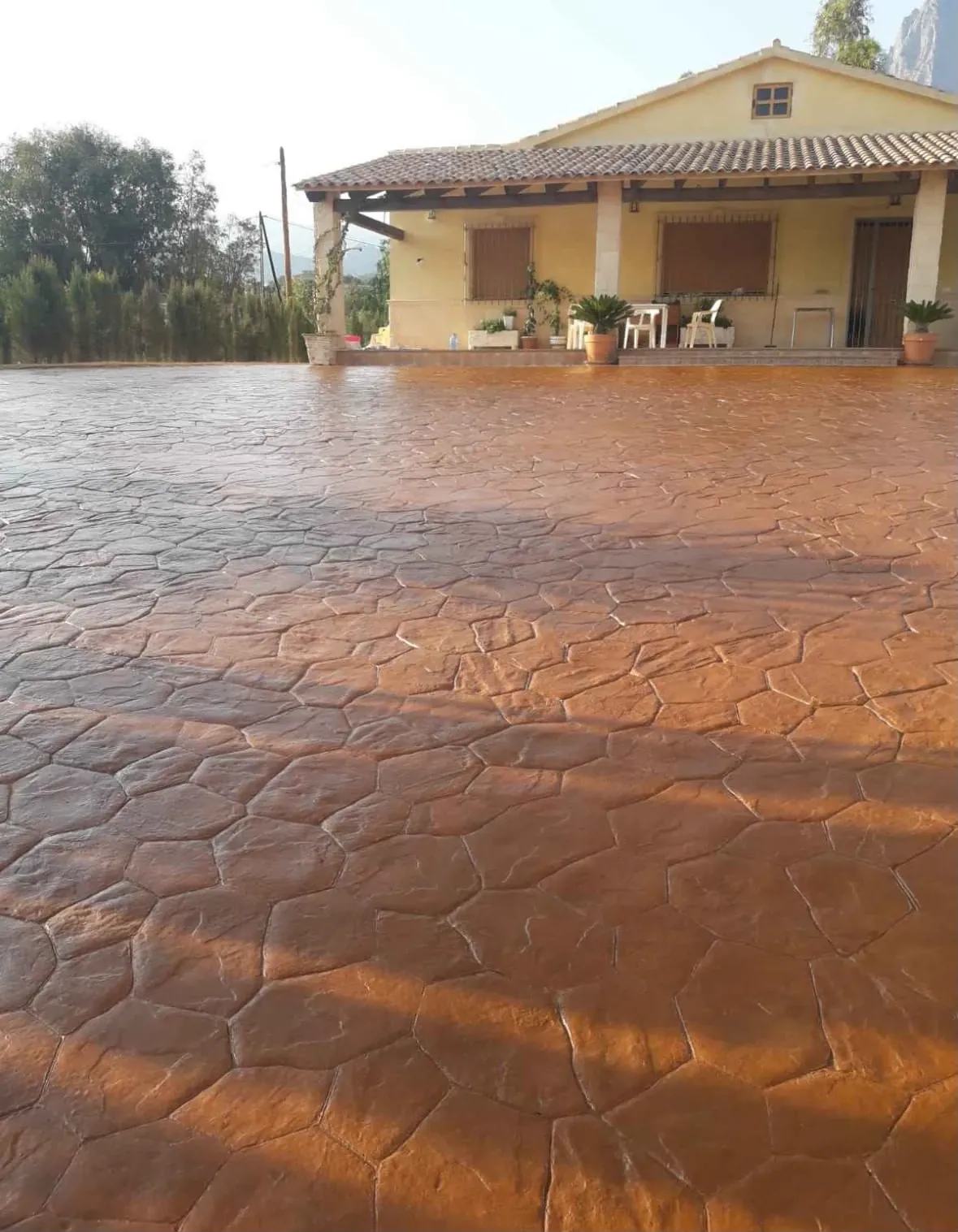 Casa de campo con un gran patio de hormigón impreso en piedra natural terracota