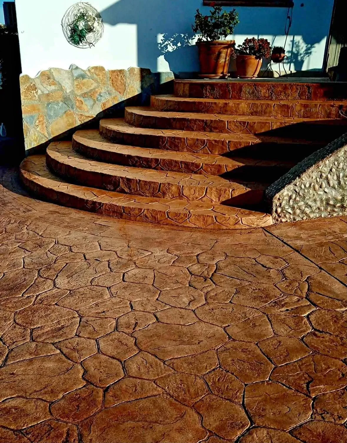 Escalera curva y suelo de hormigón impreso en piedra natural terracota
