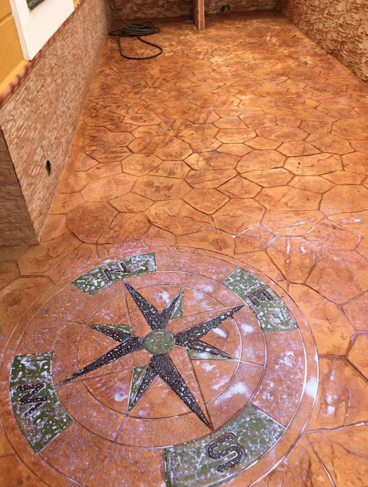 Patio de hormigón impreso en piedra natural terracota con una rosa de los vientos