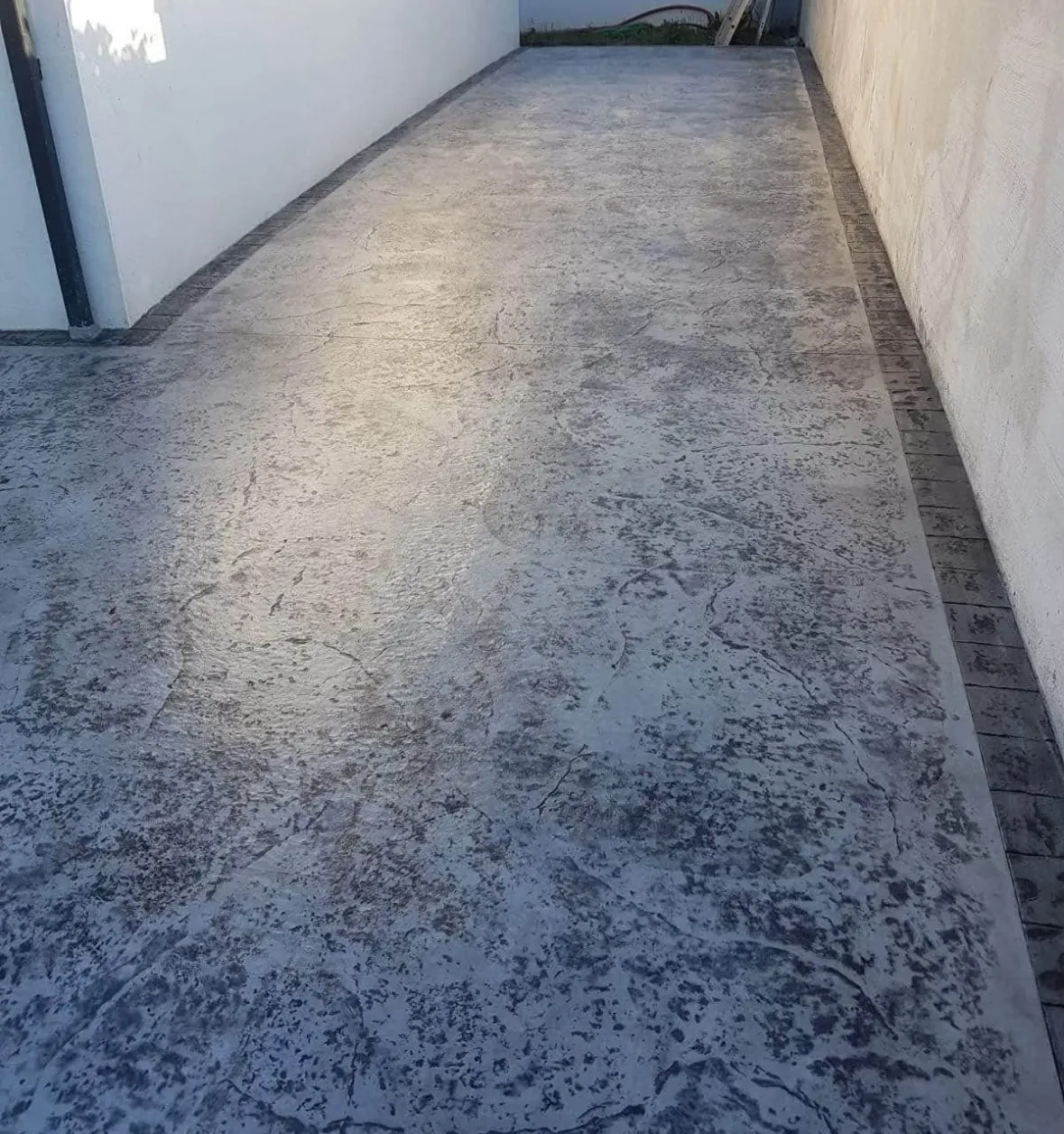 Pasillo de manta imitación mármol gris con cenefa de adoquín