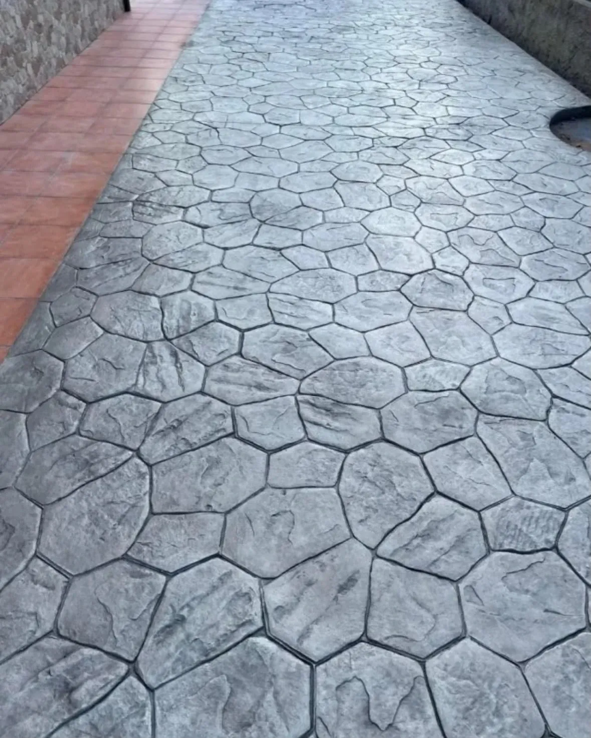 Hormigón impreso en piedra natural gris junto a baldosa terracota